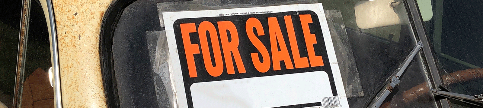 Orange and black for sale sign on a car windshield.