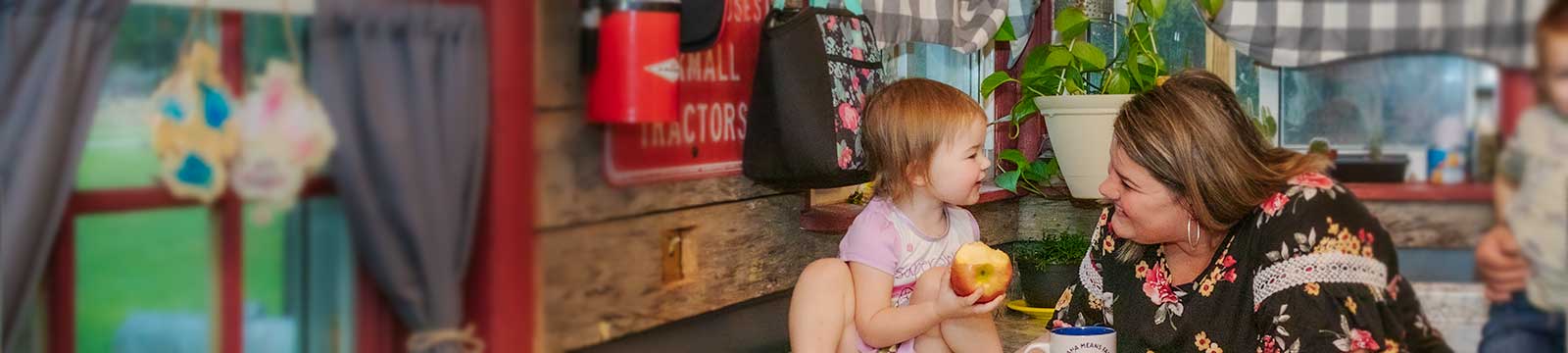 Mother eye level with her toddler daughter who is eating an apple