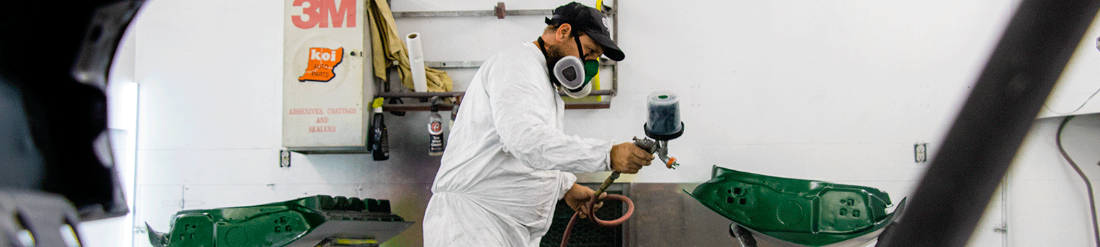 Autobody business owner spray painting car doors green in his shop.