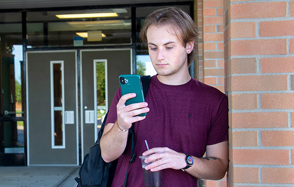 Man leaning against brick wall using phone