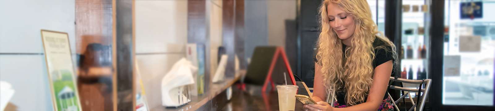 Friendship State Bank customer in Uncle Steels coffee shop checking her mobile digital banking account.