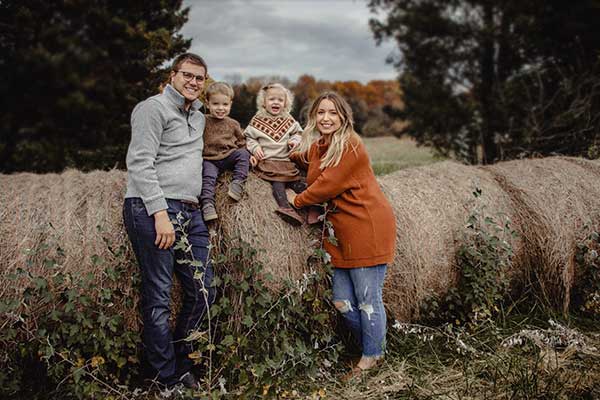 Family with two small children sitting on round hay bales in Southeastern Indiana
