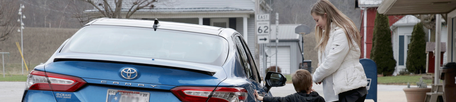 A mom opening the car door for her young son.