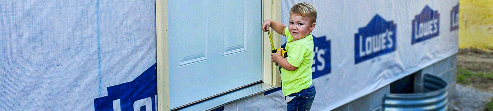 Young boy with tape measure on a construction site.