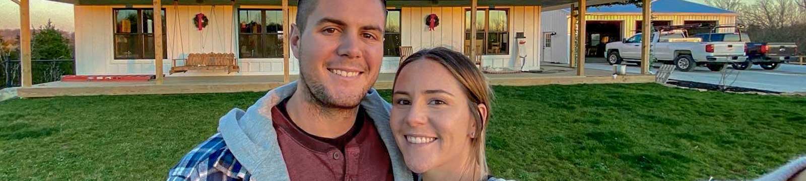 Couple smiling in front of their newly constructed home.