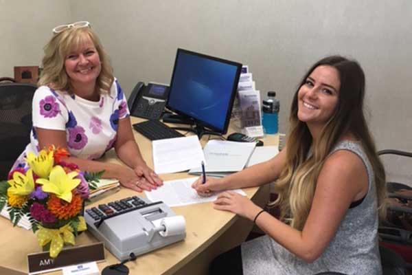 Loan officer and customer (two women) sign loan documents for customers first home purchase.