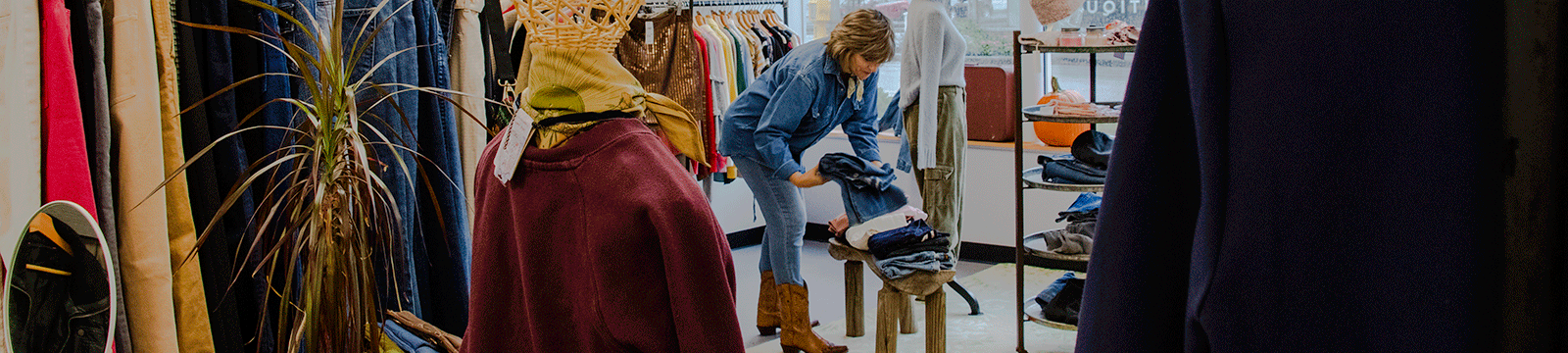 Clothing boutique owner arranging clothing items in her store.