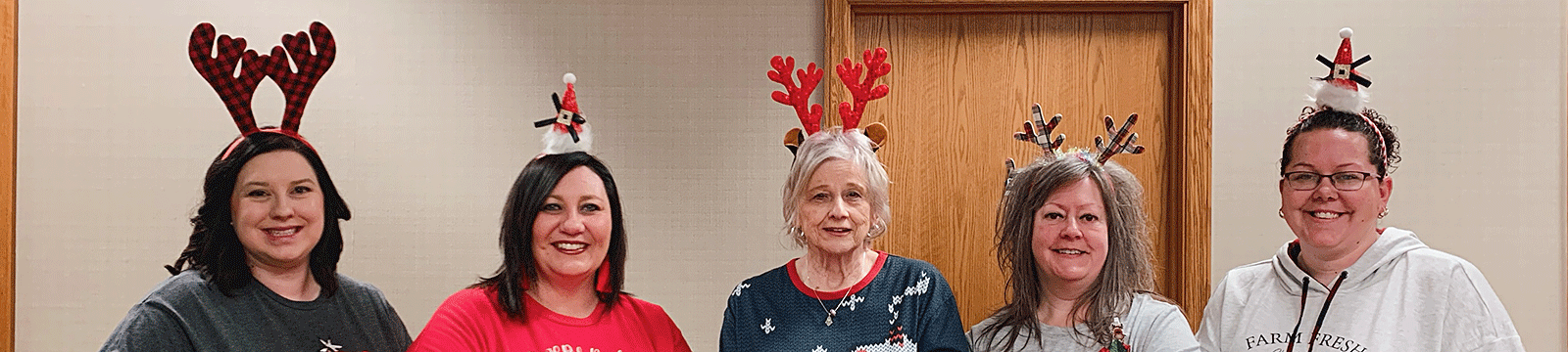 Women wearing reindeer antlers and Christmas antlers standing in a row.