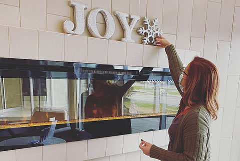 Woman putting decorations on fireplace mantal.