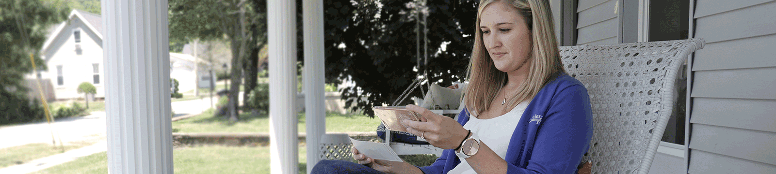 Woman on front porch using mobile deposit to deposit a check using her smart phone.