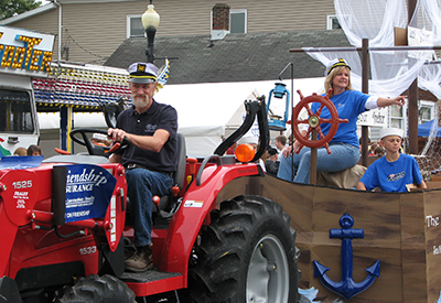 Tracy Lemon driving a tractor and pulling float decorated like a sailboat in the Versailles Pumpkin Show.
