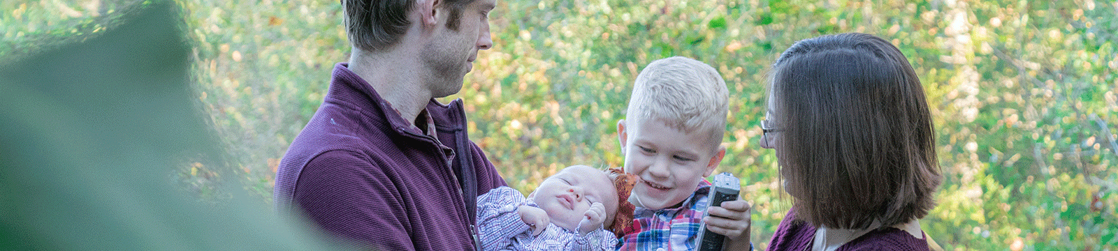 Couple outside holding two small children.