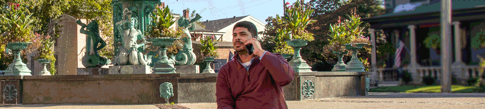 Man on phone in front of Broadway Fountain in Madison, IN.