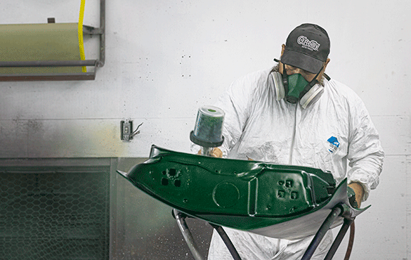 An autobody business owner painting car doors green in his shop.